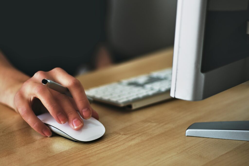 pexels photo 392018 392018 A hand using a wireless mouse at a modern desk setup with a computer and keyboard.